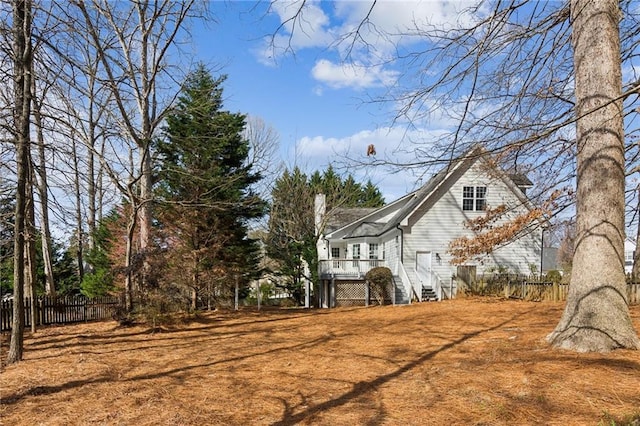 view of side of property featuring a chimney, fence, and a wooden deck