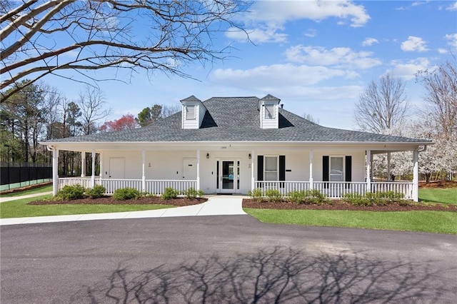 farmhouse-style home with a porch and roof with shingles