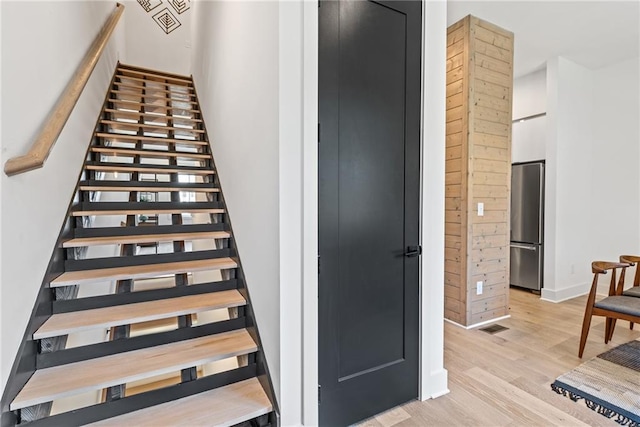 stairs featuring visible vents, baseboards, and wood finished floors