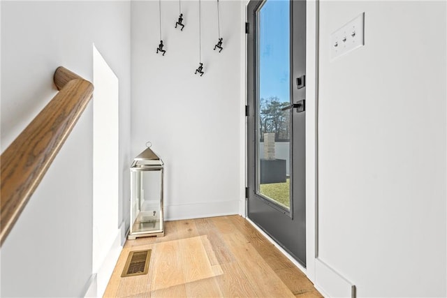 entryway with wood finished floors, baseboards, and visible vents
