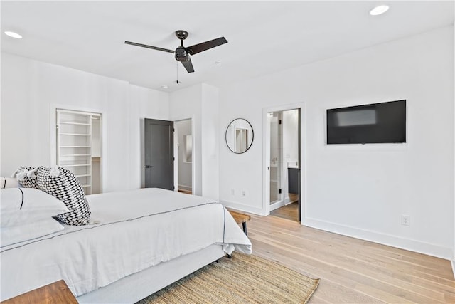 bedroom with baseboards, recessed lighting, ensuite bathroom, a walk in closet, and light wood-style floors
