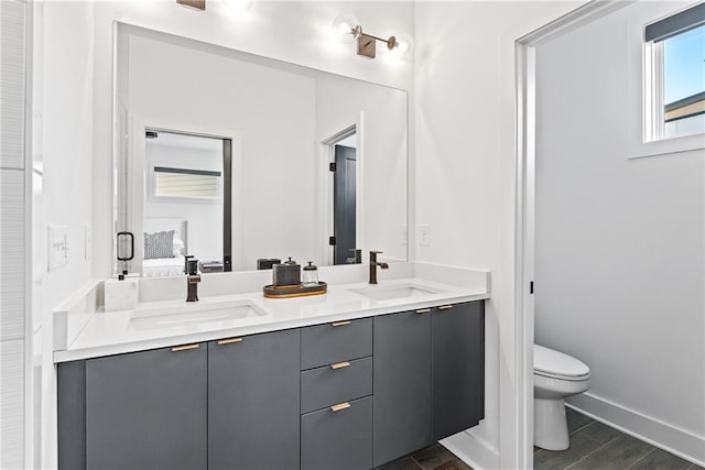 ensuite bathroom featuring double vanity, a sink, and toilet