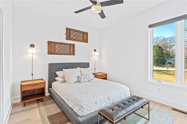 bedroom with light wood-style flooring, ceiling fan, baseboards, and visible vents