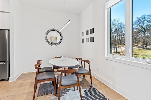 dining space with baseboards and light wood finished floors