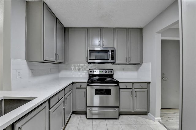3650 Ashford Dunwoody Rd NE Unit 923, Atlanta, GA 30319 - kitchen featuring appliances with stainless steel finishes, gray cabinetry, decorative backsplash, and a textured ceiling