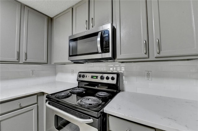 3650 Ashford Dunwoody Rd NE Unit 923, Atlanta, GA 30319 - kitchen with stainless steel appliances, gray cabinets, decorative backsplash, and light stone countertops