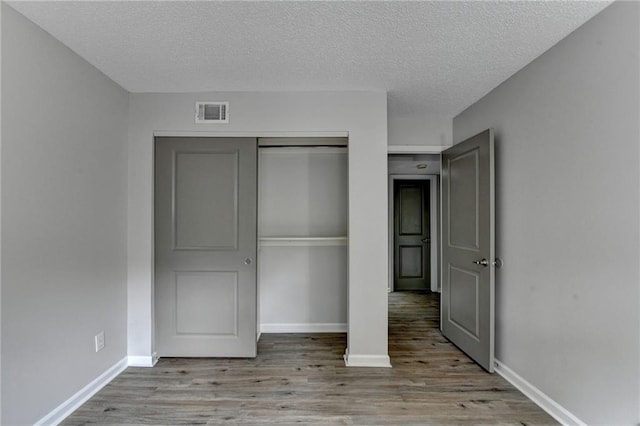 3650 Ashford Dunwoody Rd NE Unit 923, Atlanta, GA 30319 - unfurnished bedroom with wood finished floors, a textured ceiling, baseboards, and a closet