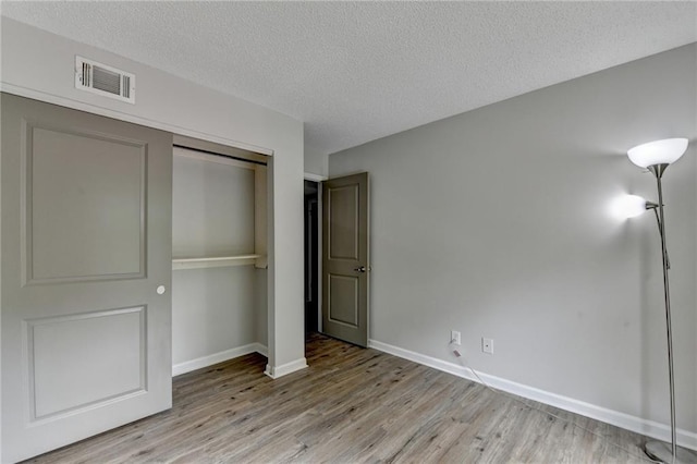 3650 Ashford Dunwoody Rd NE Unit 923, Atlanta, GA 30319 - unfurnished bedroom featuring light wood-style floors, a closet, baseboards, and a textured ceiling