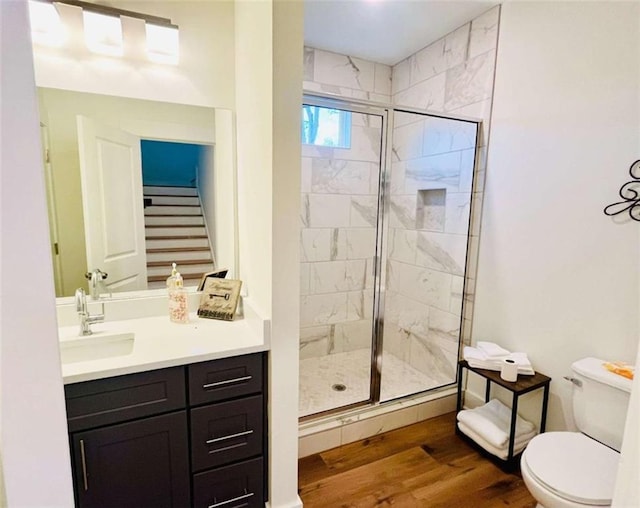 bathroom featuring toilet, a stall shower, wood finished floors, and vanity