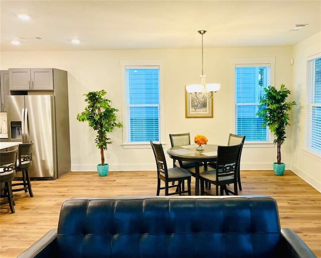 dining area featuring baseboards, light wood-style flooring, a chandelier, and a wealth of natural light