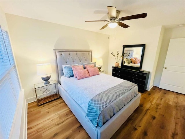 bedroom with ceiling fan, wood finished floors, and baseboards