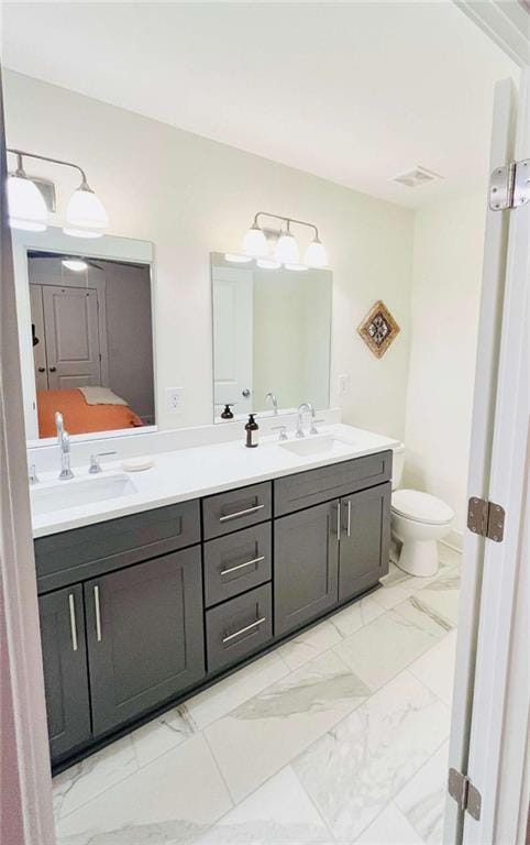 full bathroom featuring marble finish floor, double vanity, a sink, and toilet