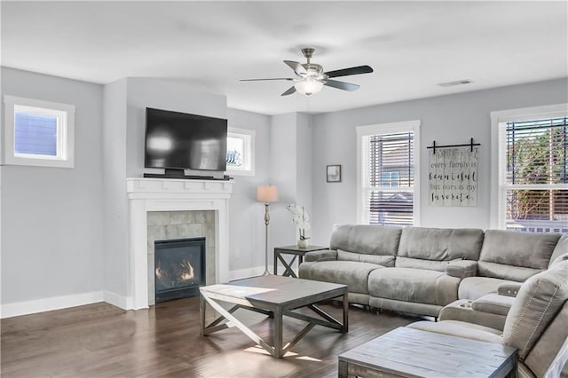 living room featuring a tile fireplace, dark hardwood / wood-style flooring, and ceiling fan