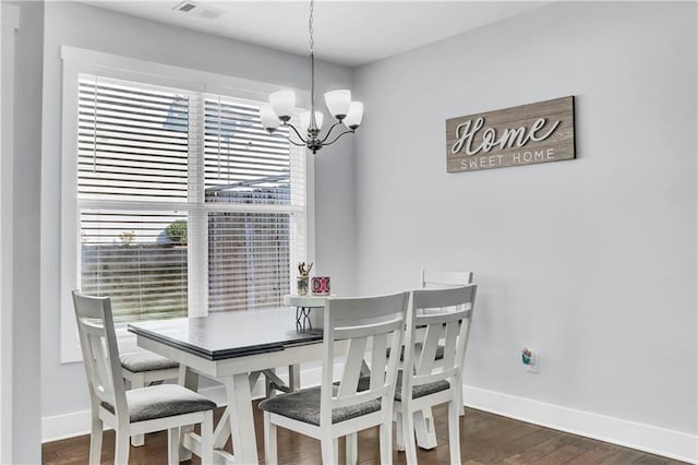 dining room with dark wood-type flooring and a chandelier