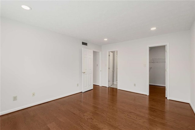 unfurnished bedroom with a walk in closet and dark hardwood / wood-style floors