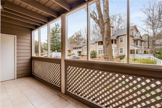 unfurnished sunroom featuring beamed ceiling and a healthy amount of sunlight