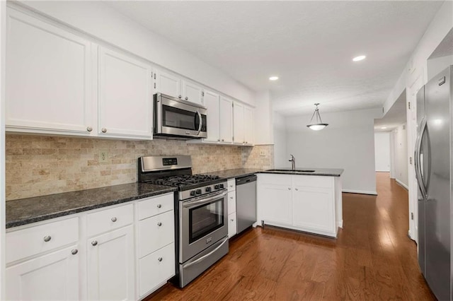 kitchen featuring pendant lighting, sink, appliances with stainless steel finishes, white cabinets, and kitchen peninsula