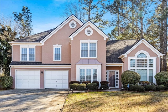 traditional-style house with a garage, concrete driveway, a front lawn, and stucco siding