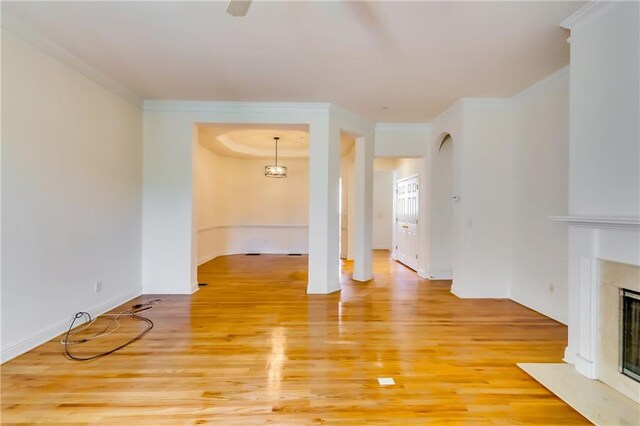 unfurnished living room featuring an inviting chandelier, hardwood / wood-style flooring, a fireplace, and ornamental molding