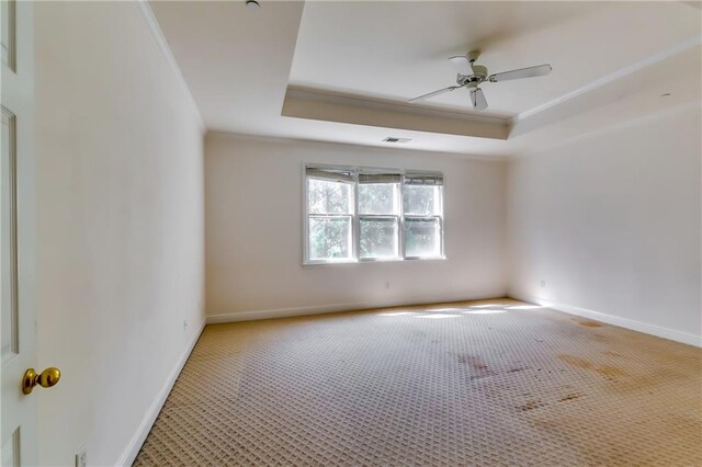 empty room featuring carpet floors, a raised ceiling, crown molding, and ceiling fan