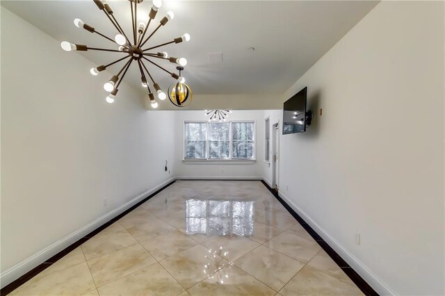 tiled spare room with a notable chandelier