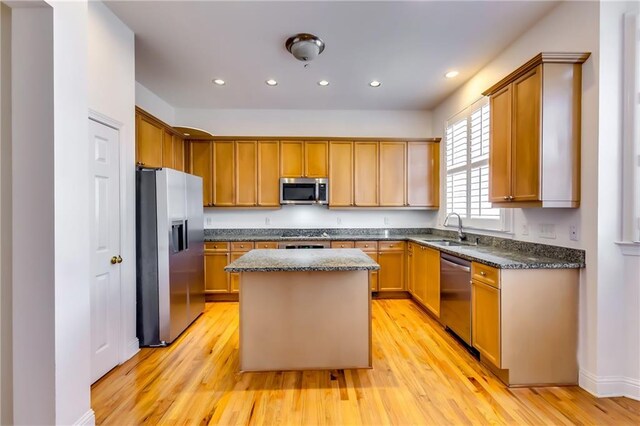 kitchen with stainless steel appliances, light wood-type flooring, a kitchen island, and sink