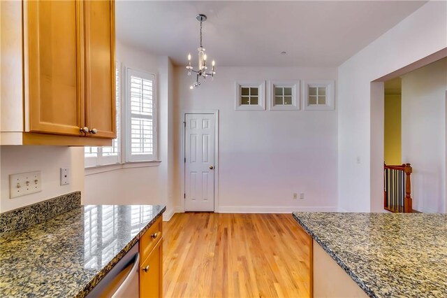 kitchen featuring decorative light fixtures, an inviting chandelier, dark stone counters, and light wood-type flooring