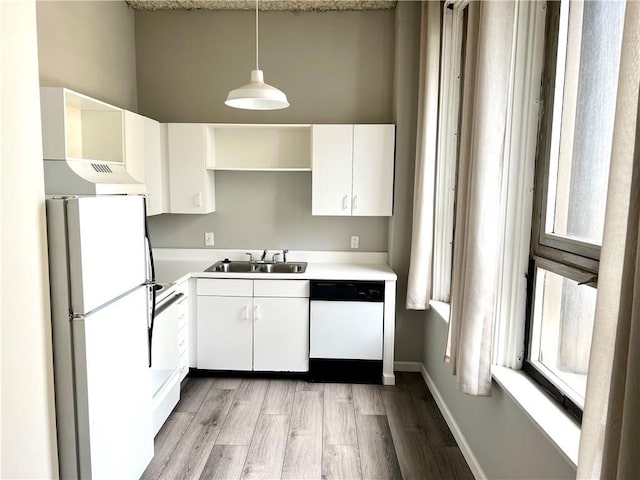 kitchen with a sink, white appliances, light wood finished floors, light countertops, and white cabinetry