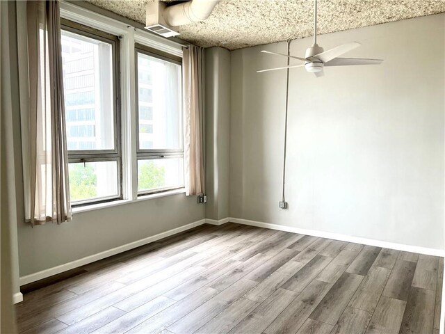 spare room featuring wood finished floors, ceiling fan, and baseboards