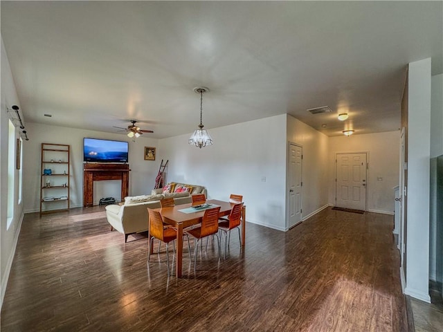 dining area featuring a barn door, dark hardwood / wood-style flooring, and ceiling fan with notable chandelier