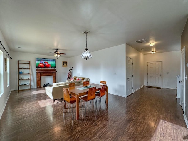 dining area with dark hardwood / wood-style floors and ceiling fan with notable chandelier