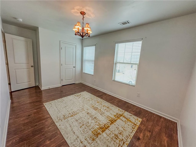 spare room with dark hardwood / wood-style flooring and a chandelier