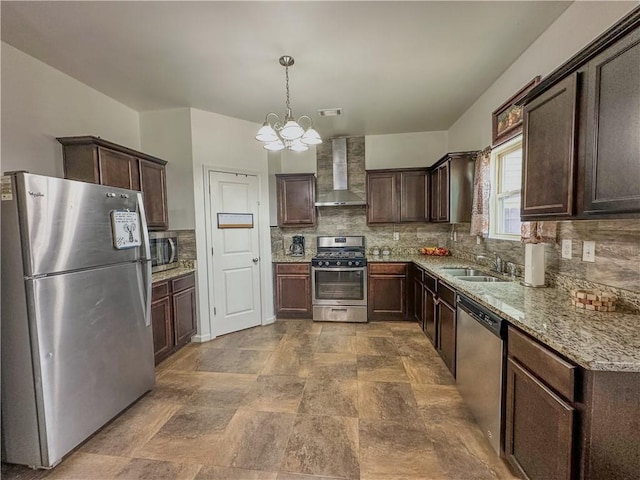 kitchen featuring wall chimney range hood, sink, appliances with stainless steel finishes, hanging light fixtures, and dark brown cabinetry