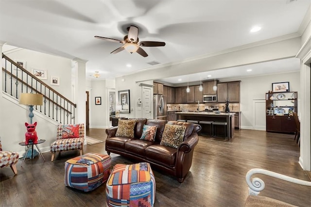 living room featuring dark wood-type flooring, ceiling fan, ornamental molding, and ornate columns