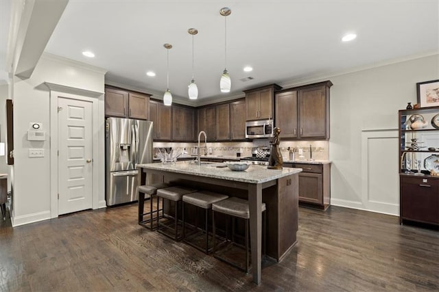 kitchen with stainless steel appliances, decorative light fixtures, a kitchen island with sink, and dark brown cabinetry