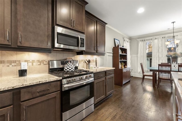 kitchen featuring appliances with stainless steel finishes, ornamental molding, dark brown cabinets, pendant lighting, and dark wood-type flooring