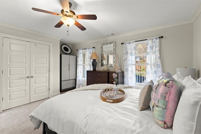 bedroom featuring ornamental molding, ceiling fan, a closet, and light carpet