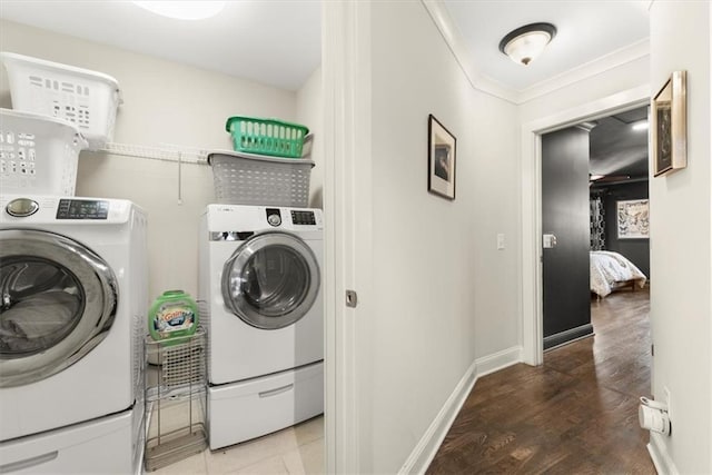 laundry area with ornamental molding, washing machine and clothes dryer, and hardwood / wood-style floors