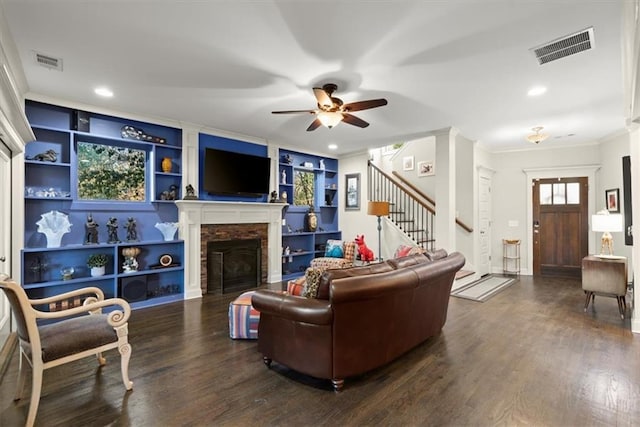 living room featuring a stone fireplace, ceiling fan, ornamental molding, hardwood / wood-style flooring, and built in shelves