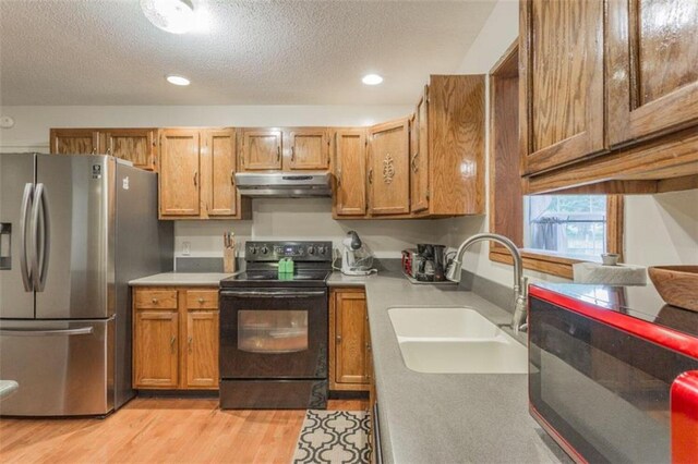 kitchen with light hardwood / wood-style flooring, sink, black appliances, and a textured ceiling