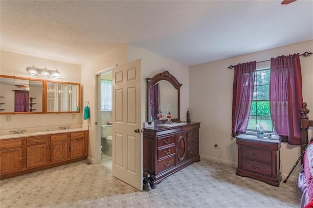 interior space with ceiling fan, vanity, a textured ceiling, and toilet