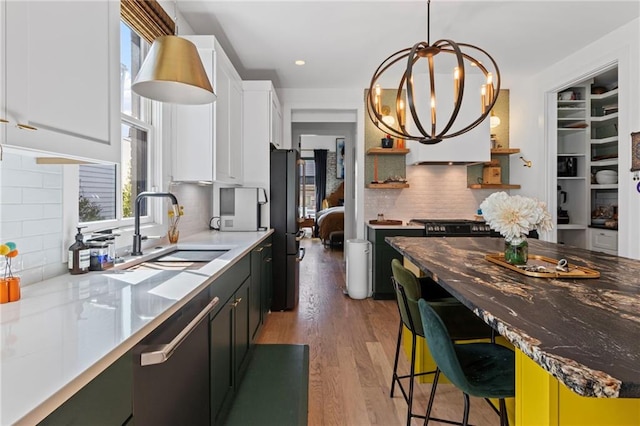 kitchen with tasteful backsplash, white cabinets, open shelves, a sink, and a kitchen breakfast bar
