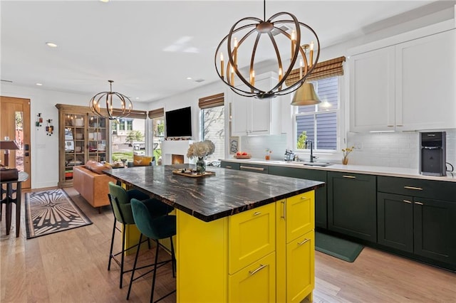 kitchen featuring a notable chandelier, a sink, light wood finished floors, recessed lighting, and green cabinets