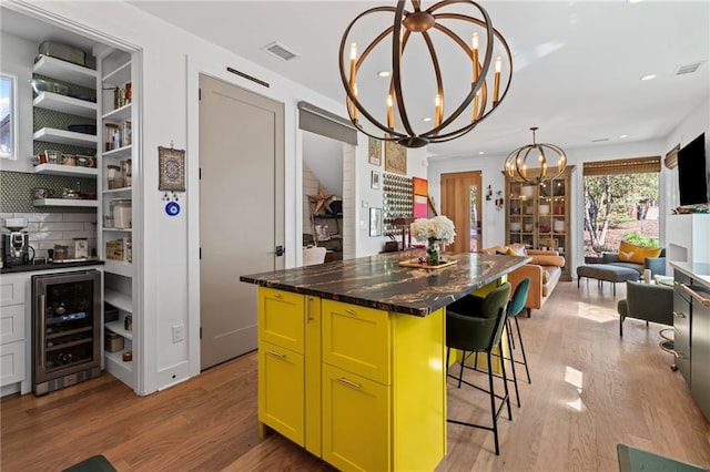 kitchen with a notable chandelier, light wood-style floors, a kitchen bar, wine cooler, and green cabinets