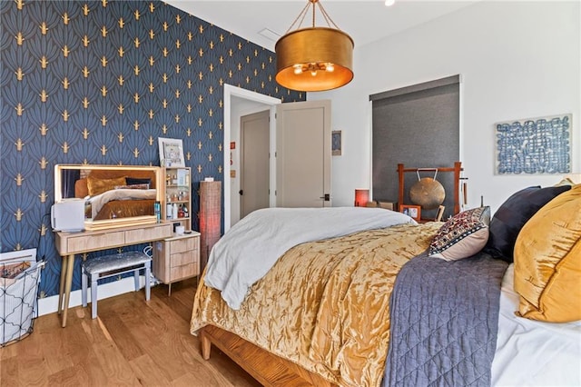 bedroom featuring wood finished floors and wallpapered walls
