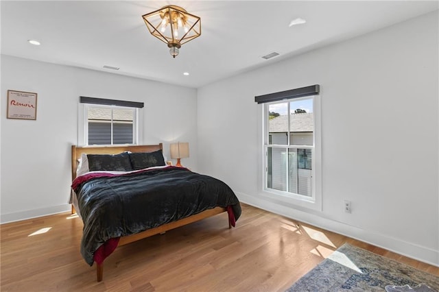 bedroom featuring wood finished floors, baseboards, and visible vents