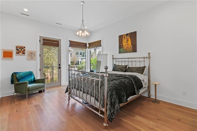 bedroom featuring baseboards, a chandelier, visible vents, access to exterior, and wood finished floors