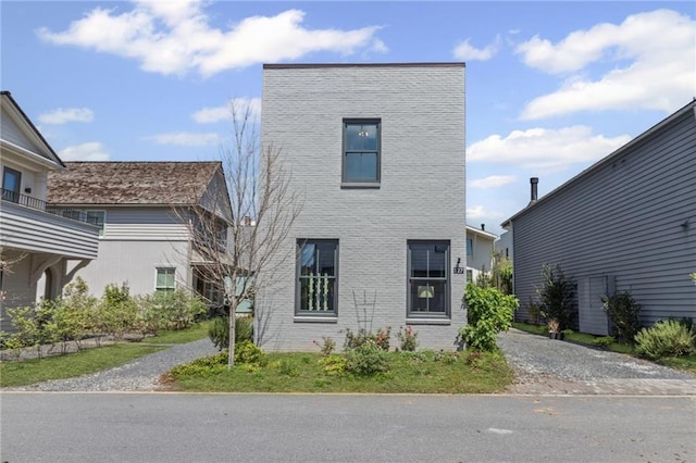 view of front of home featuring gravel driveway and brick siding
