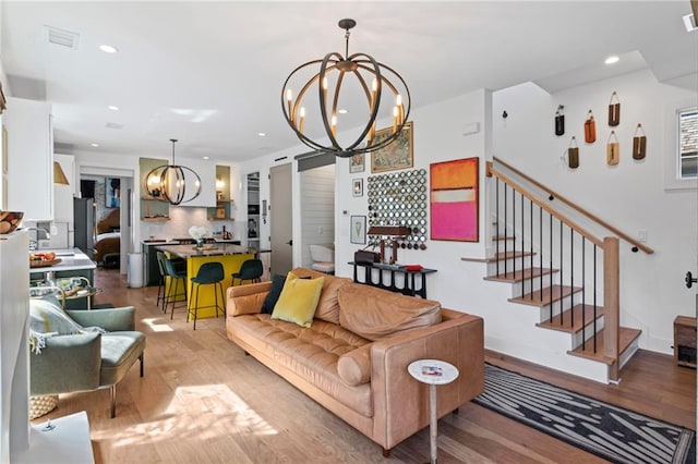 living area featuring a notable chandelier, light wood-type flooring, recessed lighting, stairs, and visible vents