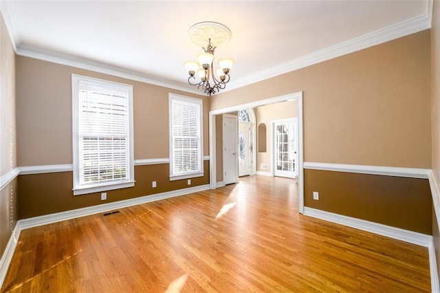 unfurnished room featuring hardwood / wood-style floors, a notable chandelier, and crown molding